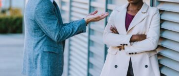 Frustrated mixed-race young couple having argument and quarrelling with each other outdoors in the street.
