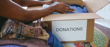 A woman packing a box labeled "donation box" on it.