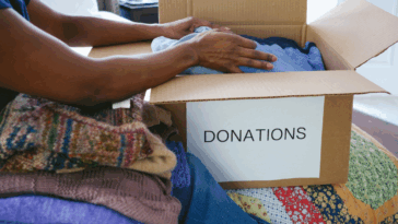 A woman packing a box labeled "donation box" on it.