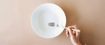 A woman resting a fork on an empty plate