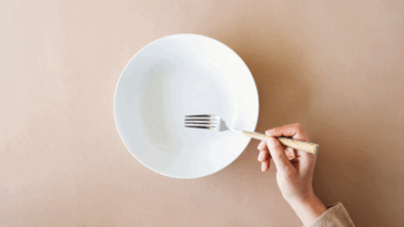 A woman resting a fork on an empty plate