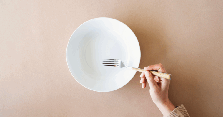 A woman resting a fork on an empty plate