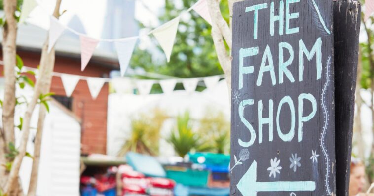 Shot of a a sign saying "The Farm Shop" with an arrow pointing towards the farm.