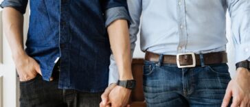 Close up shot of a gay couple holding hands. Focus on their hands.