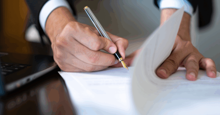 A man signing a paper document.