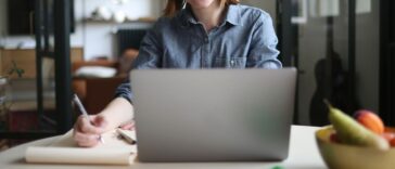 A young woman teleworking at the kitchen table.