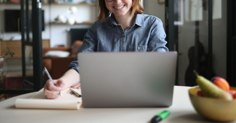 A young woman teleworking at the kitchen table.