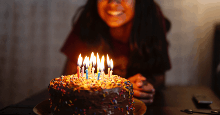 A teenage girl blowing out birthday candles.