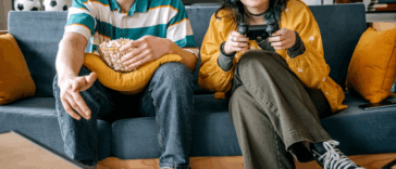 two people seated on couch playing video games