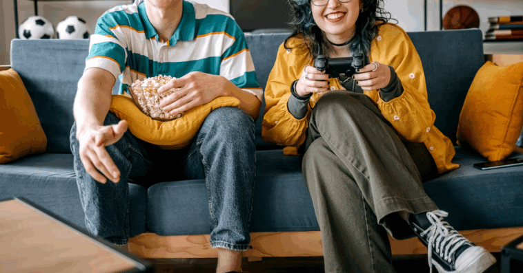 two people seated on couch playing video games