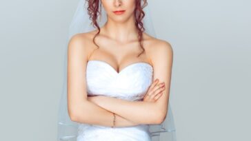 Grumpy bride. Sad and disappointed hesitating woman in wedding dress, arms folded, unhappy wife.