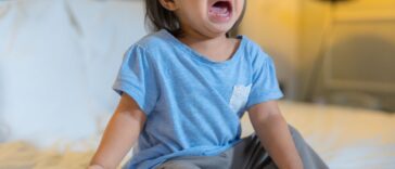 Toddler girl crying on the bed.