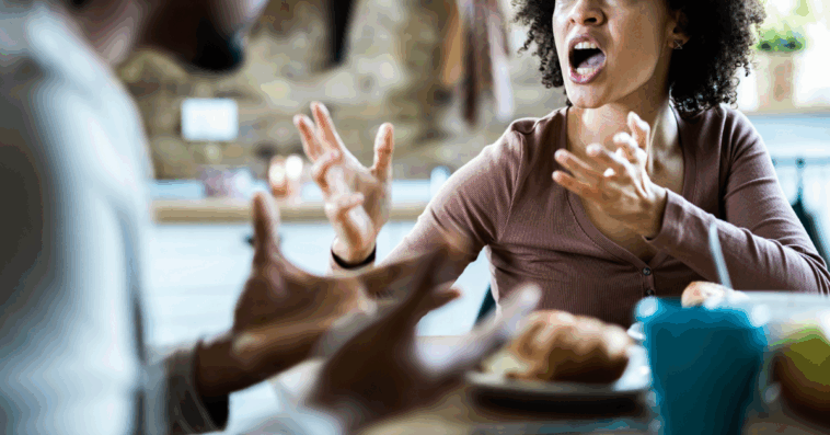 A woman emphatically gesturing at a man across a table from her.