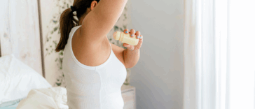 A woman putting on deoderant.