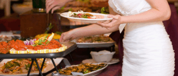 A bride taking food from a buffet.