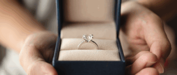 A woman holding a ring box open to reveal an engagement ring.