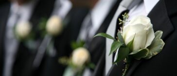 Unidentifiable groomsmen in black wearing white rose boutonnieres.