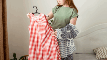 A woman. looking at a red checkered dress on a hanger.