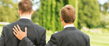 Two men in suits, with one resting his hand on the other's shoulder.