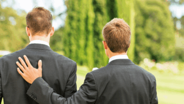 Two men in suits, with one resting his hand on the other's shoulder.