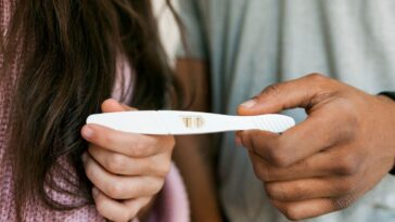 Young couple holding positive pregnancy test.