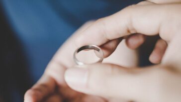 A close-up view of a young couple's hands holding a wedding ring.