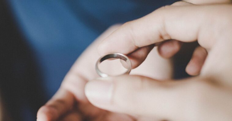 A close-up view of a young couple's hands holding a wedding ring.