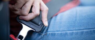Close up of a woman's hand pulling a seat belt in her car.