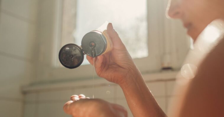 Woman putting hair shampoo on her hand , ready for hair washing.
