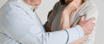 A man putting his arm around a woman with her head resting in her hand.