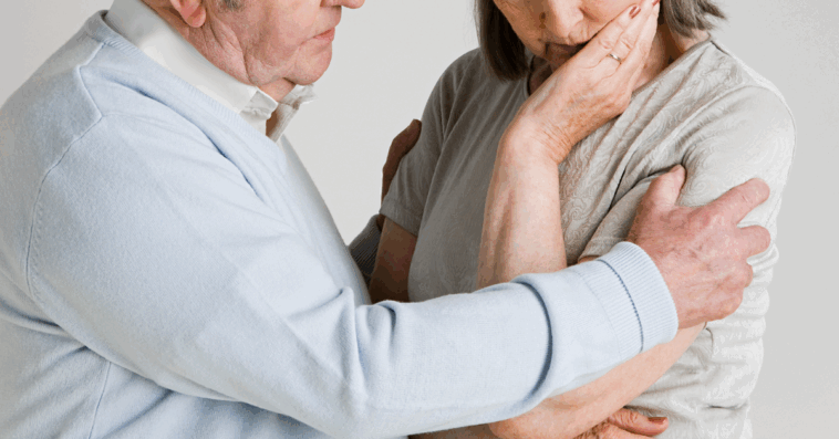 A man putting his arm around a woman with her head resting in her hand.