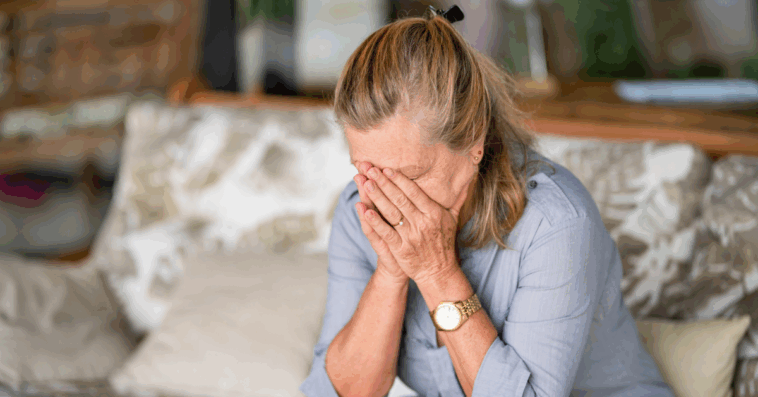 A woman sitting on the. sofa with her head in her hands.