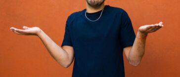 A young man shrugging his shoulders with hands spread out.