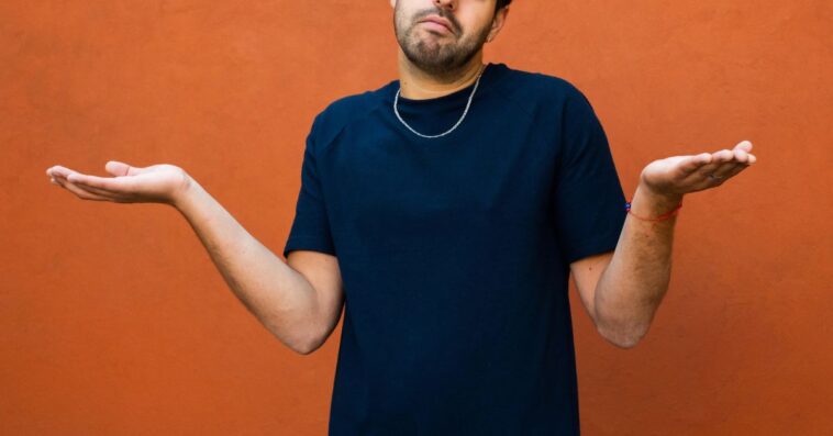 A young man shrugging his shoulders with hands spread out.