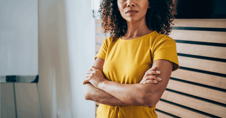 A woman in a yellow dress with her arms crossed.