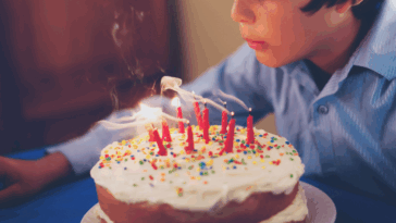 boy blowing out candles on birthday cake