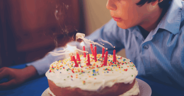 boy blowing out candles on birthday cake