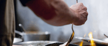 person cooking meat with butter