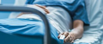 In the Hospital Sick Male Patient Sleeps on the Bed. Heart Rate Monitor Equipment is on His Finger.