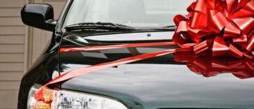 New black car with red ribbon on the hood.