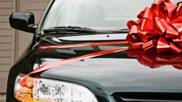 New black car with red ribbon on the hood.