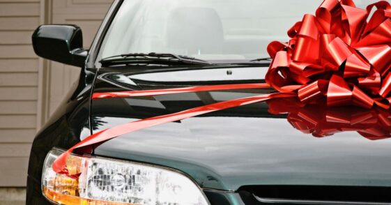 New black car with red ribbon on the hood.