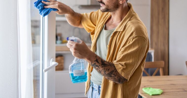 A man cleaning windows at home, ensuring a clear and fresh view. This scene emphasizes the importance of home maintenance and creating a tidy, pleasant living environment.