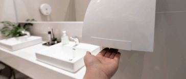 A man drying his hands under an electric handr