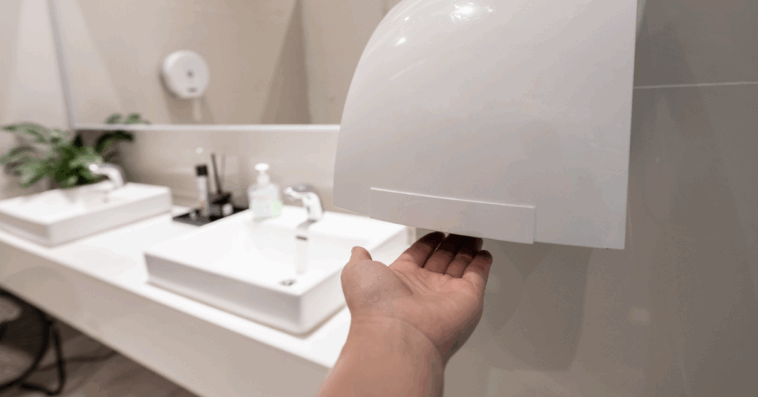 A man drying his hands under an electric handr