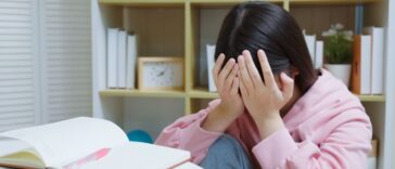 Young, crying girl studying at home.