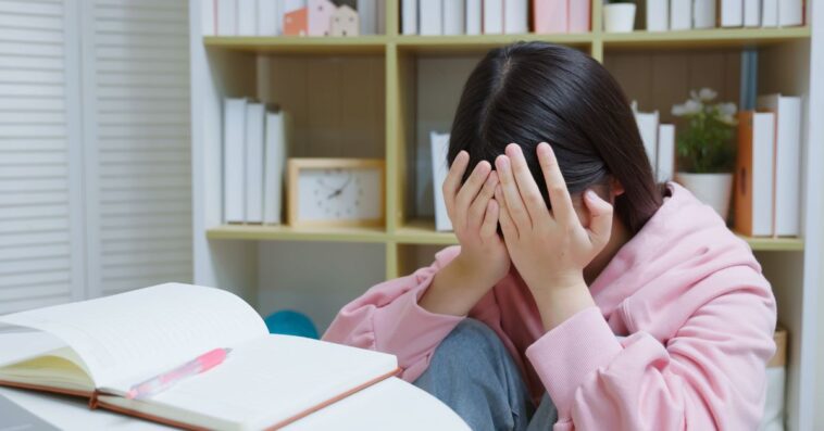 Young, crying girl studying at home.
