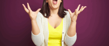 A woman screaming throwing her hands in the air.