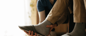 A woman helping a man take off his slippers.