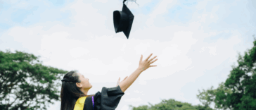 A woman throwing a graduation cap in the air.